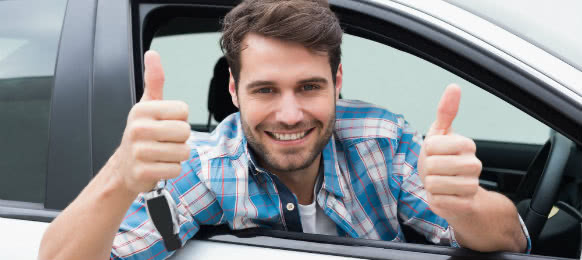 happy guy giving a thumbs up sign inside his new car